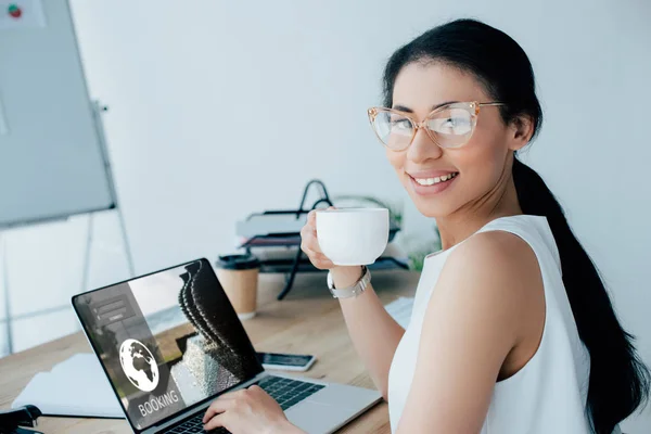 Sonriente Mujer Negocios Latina Sosteniendo Taza Café Mientras Usa Ordenador — Foto de Stock