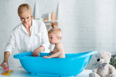 neşeli anne evde banyo alarak sevimli yürümeye başlayan oğlu bakarak 