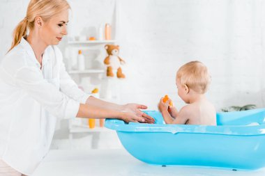 evde banyo alarak neşeli sarışın anne yakın sevimli yürümeye başlayan çocuk 