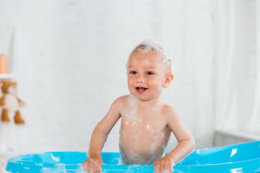 banyo ve mavi plastik bebek küvette gülümseyen sevimli yürümeye başlayan çocuk 
