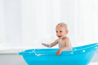 banyo ve mavi plastik bebek küvette gülümseyen sevimli yürümeye başlayan çocuk 