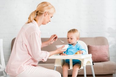 sarışın anne kase tutan ve evde sevimli küçük oğlu besleme 