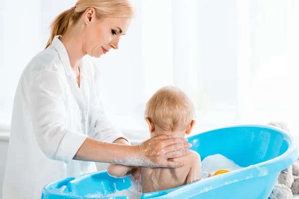 Rubia Madre Lavado Mirando Niño Pequeño Hijo Azul Bebé Bañera — Foto de Stock