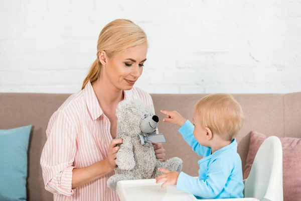 Aranyos Kisgyermek Fia Mutat Ujjal Teddy Bear Közelében Vidám Anya — Stock Fotó
