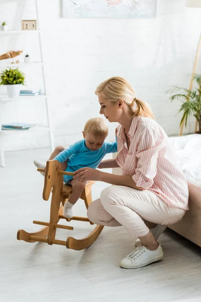 Niño Pequeño Caballo Mecedora Madera Cerca Madre Rubia Dormitorio — Foto de Stock