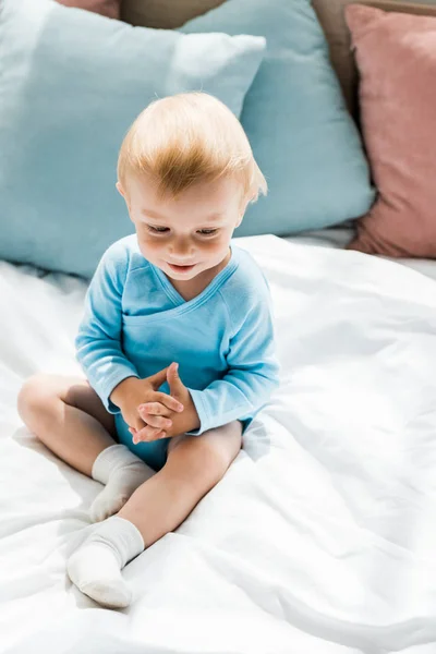 自宅でベッドに座ってかわいいと笑顔の幼児の子供のオーバーヘッドビュー — ストック写真
