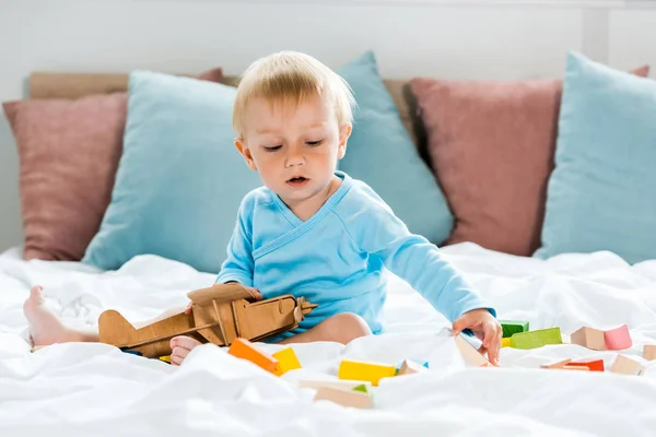 Criança Brincando Com Biplano Madeira Perto Blocos Brinquedos Coloridos Cama — Fotografia de Stock