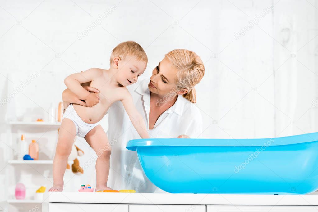 low angle view of happy mother looking at cute toddler son in bathroom 