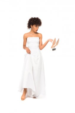 Afrikalı Amerikan gelin dokunmadan gelinlik ve tutarak ayakkabı beyaz üzerinde izole ayakta 