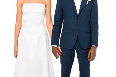 cropped view of african american bride and bridegroom holding hands while standing isolated on white  clipart