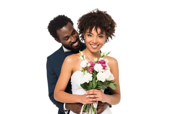 Lächelnd Afrikanisch Amerikanischer Bräutigam Umarmt Attraktive Braut Hält Blumen Isoliert — Stockfoto