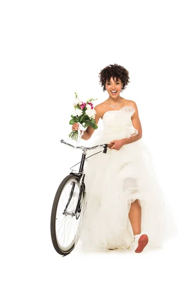 陽気なアフリカ系アメリカ人の花嫁が自転車で立ち 白に隔離された花を持っている — ストック写真