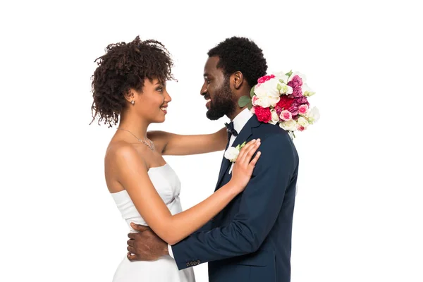 Happy African American Bride Hugging Bridegroom While Holding Flowers Isolated Stock Photo