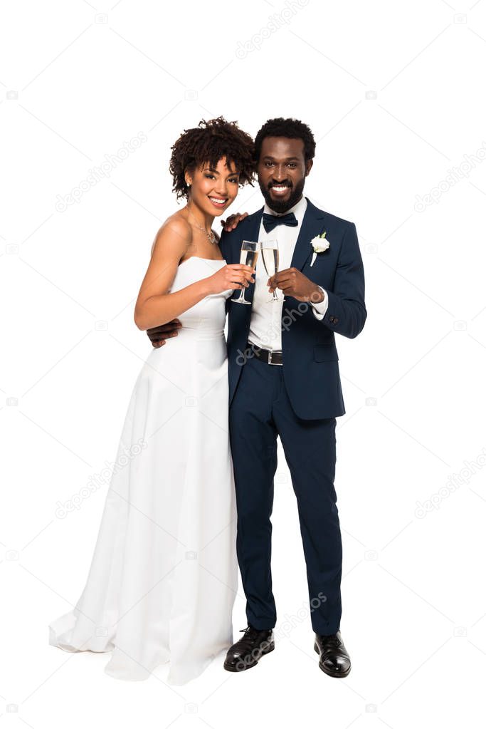 cheerful african american bride and bridegroom holding champagne glasses isolated on white 