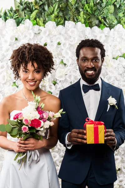 欢快的非洲美国新娘拿着鲜花附近的新郎与礼物 — 图库照片