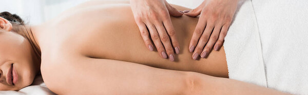 panoramic shot of masseur doing massage to woman in spa center