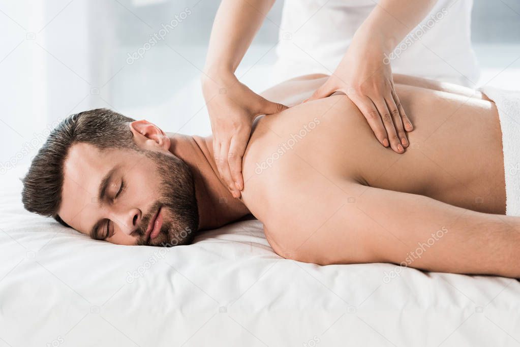 handsome bearded man lying on massage table during massage 