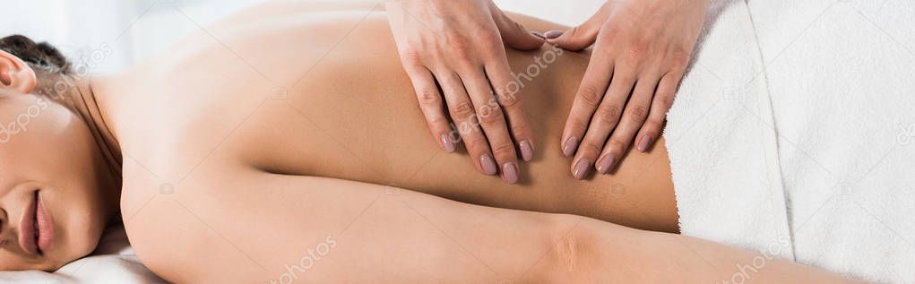 panoramic shot of masseur doing massage to woman in spa center