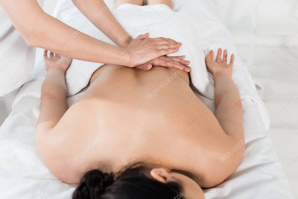 cropped view of masseur doing massage to woman in spa center 