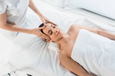 masaj masasında güzel bir kadına baş masajı yapan masör havai görünümü 