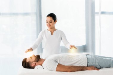 attractive woman putting hands above body while healing handsome bearded man  clipart