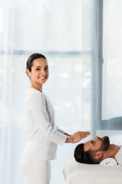 mutlu şifacı kapalı gözlü genç adamın başının üzerinde ellerini koyarak 