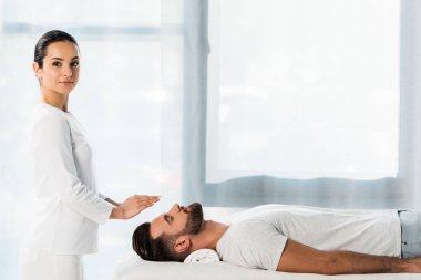 güzel şifacı kapalı gözleri ile adamın başının üzerinde ellerini koyarak 