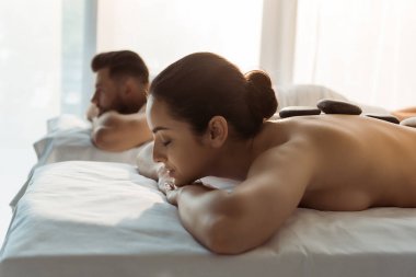 kapalı gözlü esmer kadının seçici odak adam yakınında taş masajı olan 