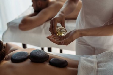 spa merkezinde kadın ve erkek yakın yağ ile şişe tutan masör kırpılmış görünümü 