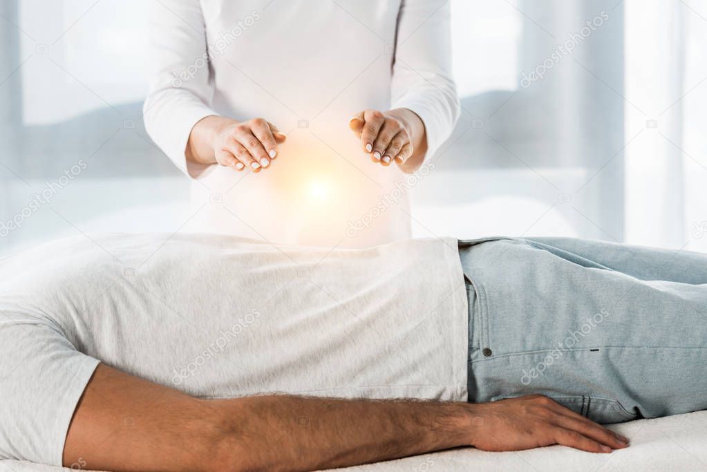 cropped view of woman putting hands above body while healing man 