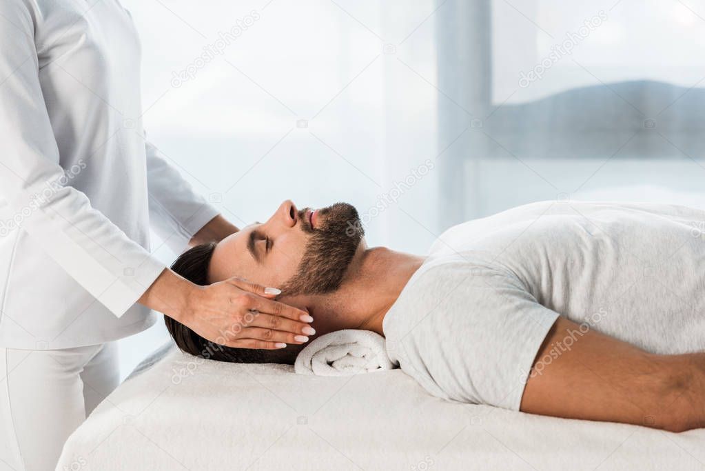 cropped view of woman healing bearded man with closed eyes 