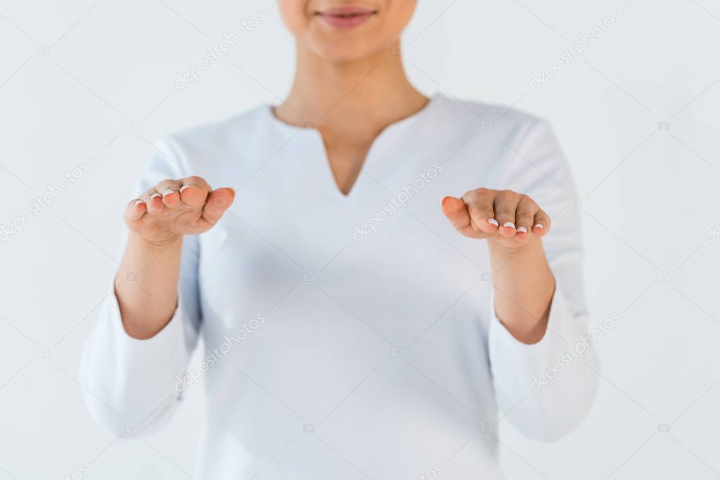 cropped view of young woman smiling while gesturing isolated on white 