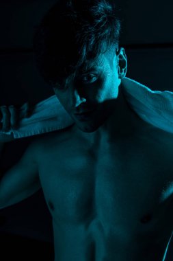 seksi gömleksiz adam havlu tutan ve karanlıkta kamera bakarak