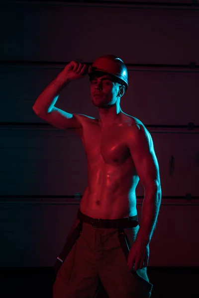 性感的无衬衫消防员在黑暗中保护安全帽 — 图库照片