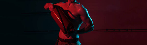 panoramic shot of sexy shirtless fireman holding fire extinguisher in darkness
