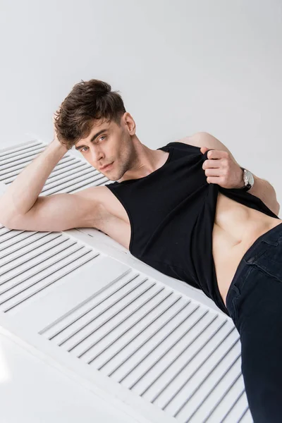 Sexy Man Zwart Mouwloos Shirt Toont Torso Terwijl Liggend Grijs — Stockfoto