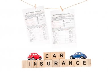toy cars, wooden blocks with letters and insurance documents isolated on white clipart