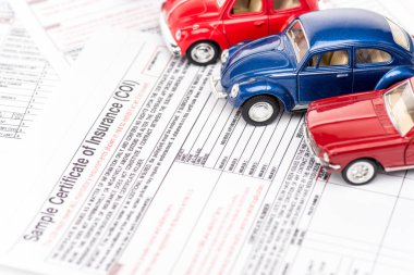 selective focus of colorful toy cars on insurance documents clipart