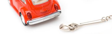 panoramic shot of red toy car and wrench on white surface clipart