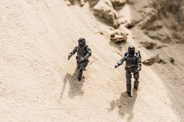 tiny toy soldiers on sand with shadows in daylight  clipart