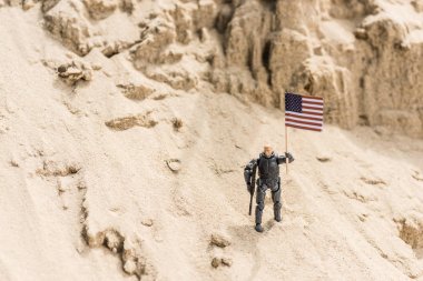 toy armed soldier standing on sand and holding american flag clipart