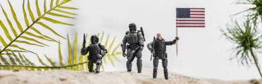 panoramic shot of toy soldiers holding american flag on sand dune clipart