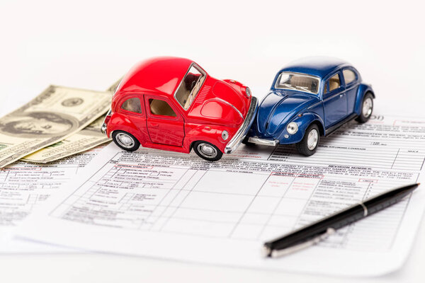 toy cars, pen, documents and dollar banknotes on white surface