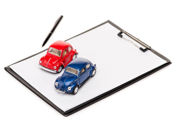 красный и синий игрушечные автомобили, буфер обмена и ручка изолированы на белом
