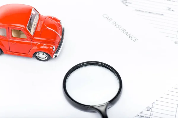 赤いおもちゃの車 虫眼鏡と保険書類 — ストック写真