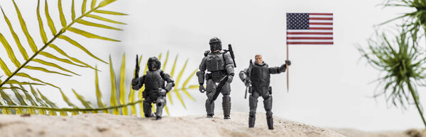 panoramic shot of toy soldiers holding american flag on sand dune