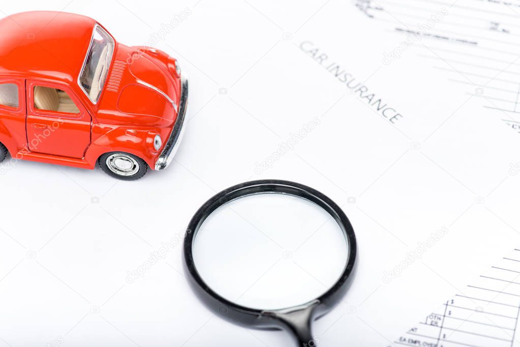 red toy car, magnifying glass and insurance documents