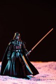 KYIV, UKRAINE - MAY 25, 2019: Darth Vader figurine with lightsaber isolated on black