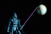 KYIV, UKRAINE - MAY 25, 2019: selective focus of Darth Vader figurine with lightsaber on black background with planet Earth