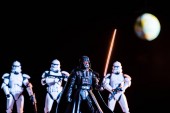KYIV, UKRAINE - MAY 25, 2019: selective focus of white imperial stormtroopers with guns and Darth Vader with lightsaber with planet Earth on background